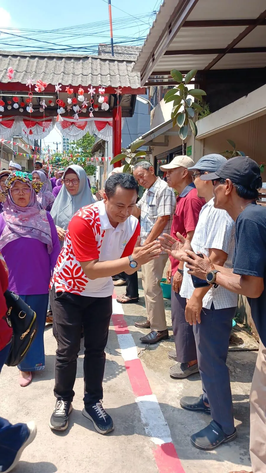 Momen hangat saat Hadi Latif, Sekretaris Desa Karanggan, menyapa warga dengan penuh ramah di acara lingkungan